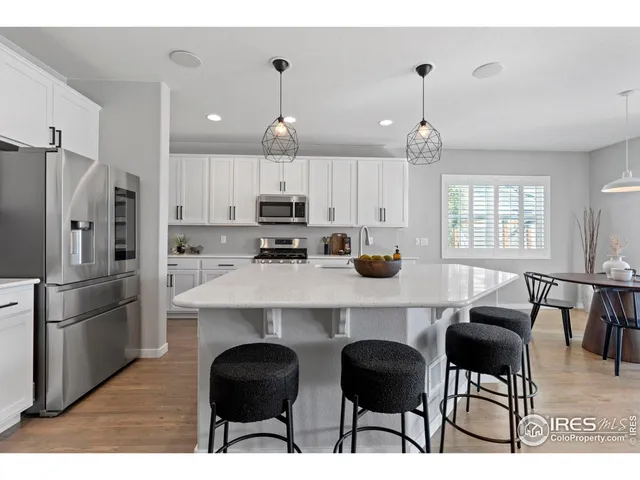 a kitchen with stainless steel appliances kitchen island granite countertop a table chairs microwave and sink