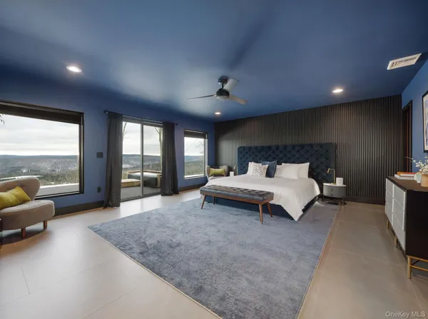 a spacious bedroom with a bed a couch and large window