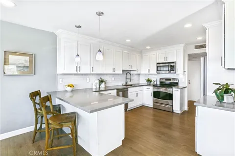 a kitchen with stainless steel appliances granite countertop a table chairs sink and cabinets