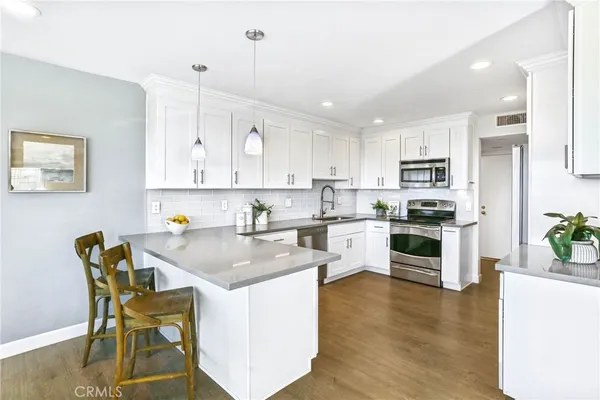 a kitchen with stainless steel appliances granite countertop a table chairs sink and cabinets