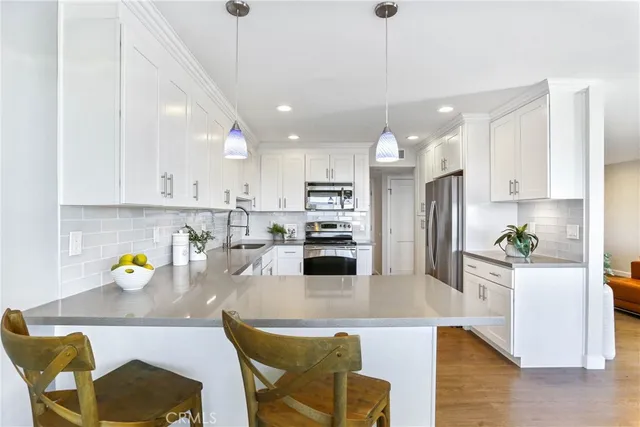 a kitchen with stainless steel appliances granite countertop a refrigerator a sink a stove a dining table and chairs with wooden floor