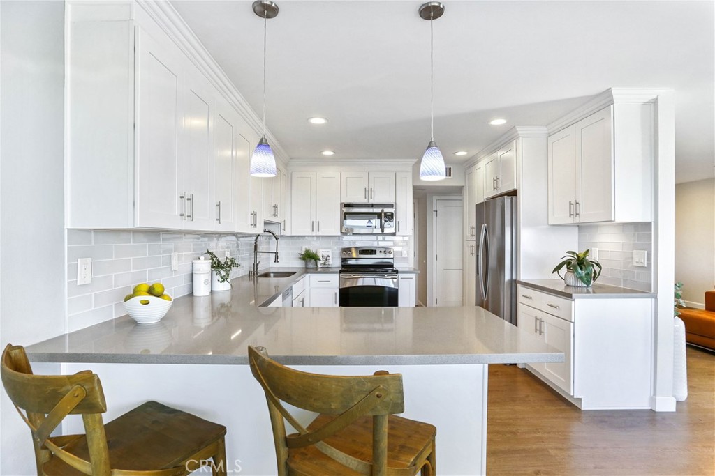 33885 Manta Court Dana Point, CA 92629 - Photo 6 of 34 a kitchen with stainless steel appliances granite countertop a refrigerator a sink a stove a dining table and chairs with wooden floor