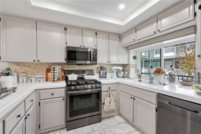 a kitchen with stainless steel appliances granite countertop white cabinets a sink a stove a microwave and a refrigerator