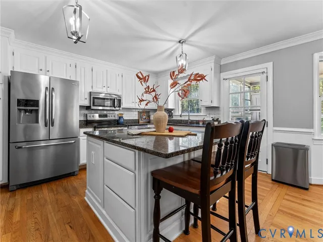 a kitchen with stainless steel appliances a dining table chairs stove refrigerator and microwave