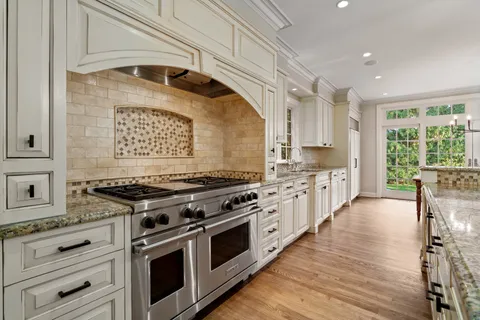 a kitchen with stainless steel appliances wooden floor stove top oven and cabinets