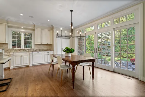 a kitchen with stainless steel appliances granite countertop a stove a refrigerator a kitchen island a table and chairs in it