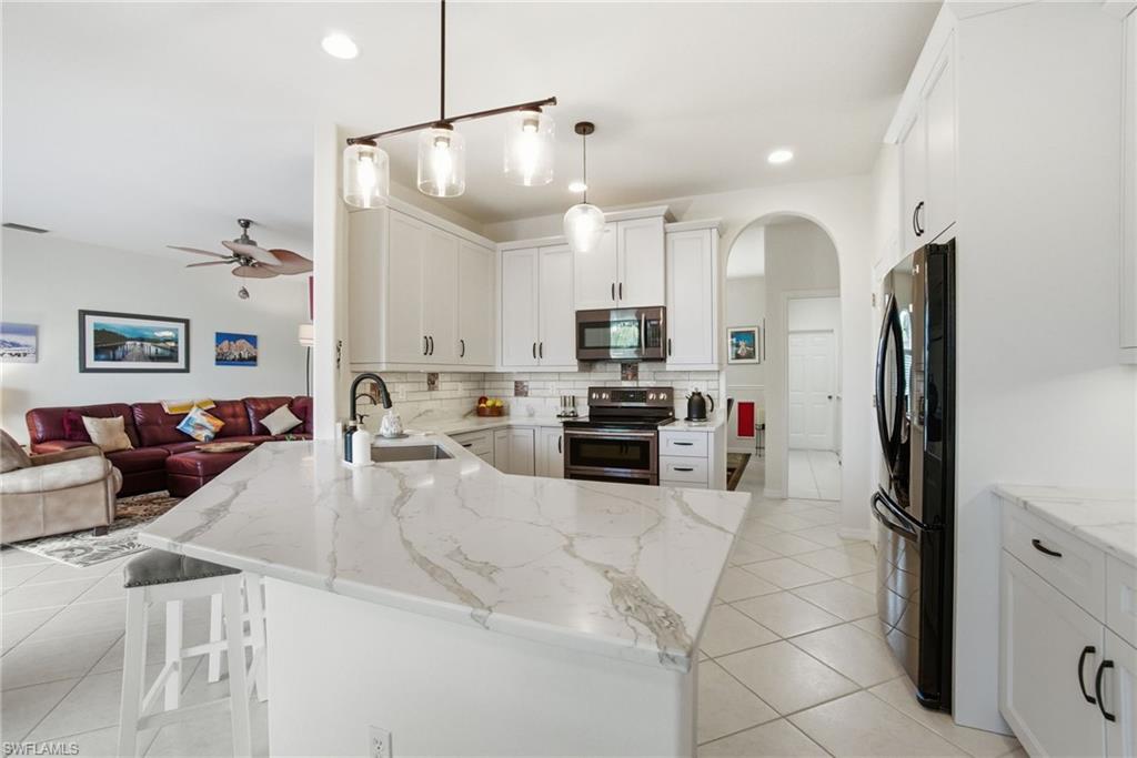 3948 Ruxton Road Naples, FL 34116 - Photo 13 of 43 a kitchen with stainless steel appliances a refrigerator sink and cabinets