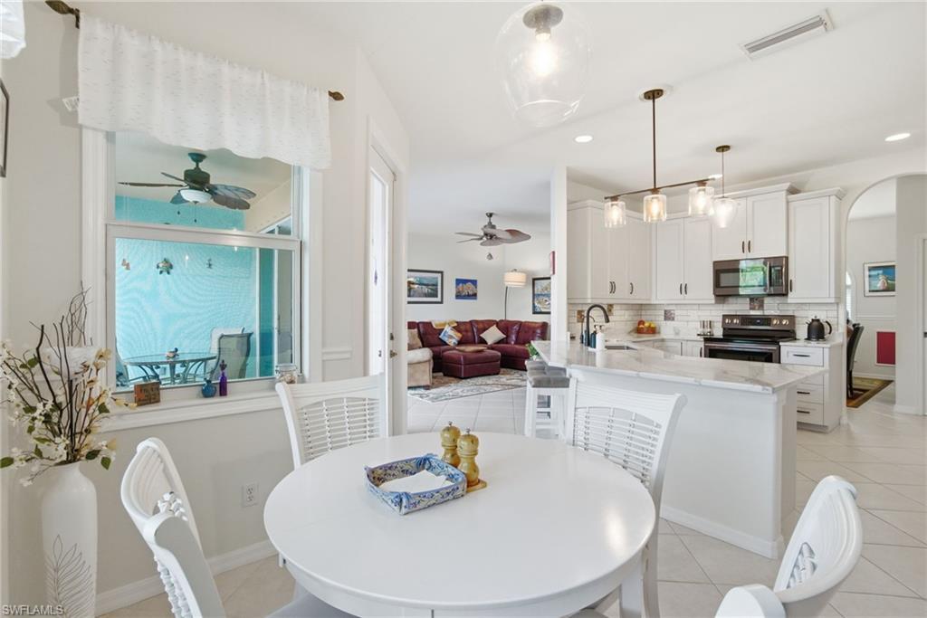 3948 Ruxton Road Naples, FL 34116 - Photo 19 of 43 a kitchen with stainless steel appliances granite countertop a stove a kitchen island a dining table and chairs