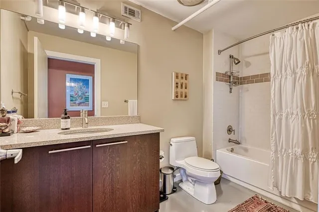 a bathroom with a granite countertop sink toilet a mirror a bathtub and shower