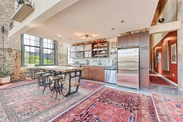 a kitchen with stainless steel appliances granite countertop a refrigerator a stove a dining table and chairs with wooden floor