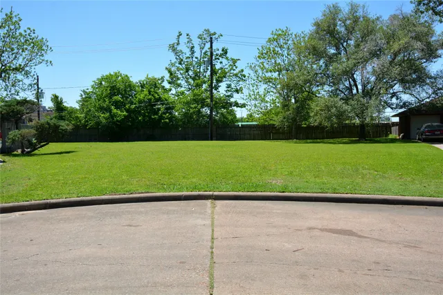 a view of a field with a small yard and large trees
