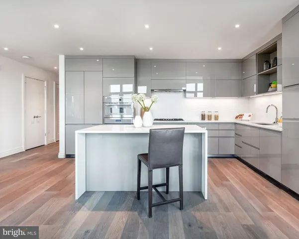 a kitchen with stainless steel appliances a dining table chairs microwave and sink