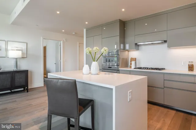 a kitchen with kitchen island a stove a sink a refrigerator and a dining table with wooden floor