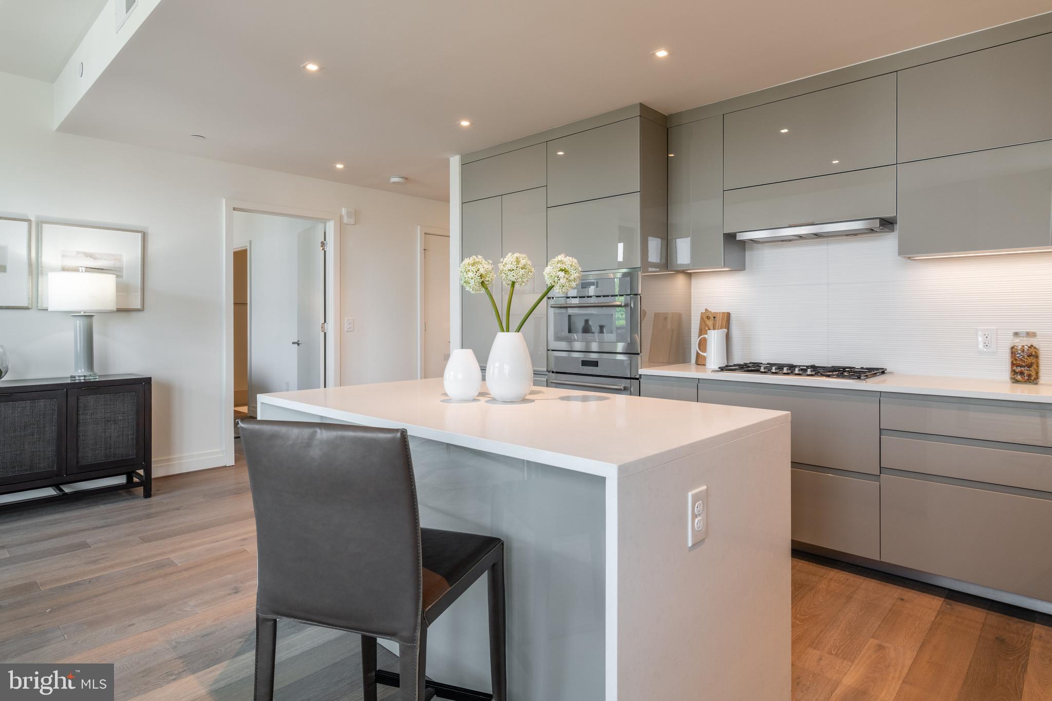 810 O Street Northwest, Unit 706 Washington, DC 20001 - Photo 21 of 48 a kitchen with kitchen island a stove a sink a refrigerator and a dining table with wooden floor