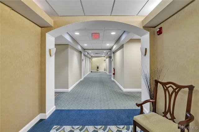 a view of a hallway with a couch and a dining table with wooden floor