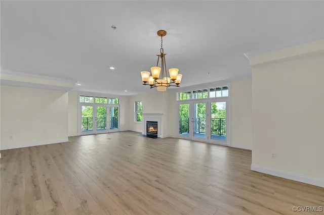 a view of a room with wooden floor chandelier and a window
