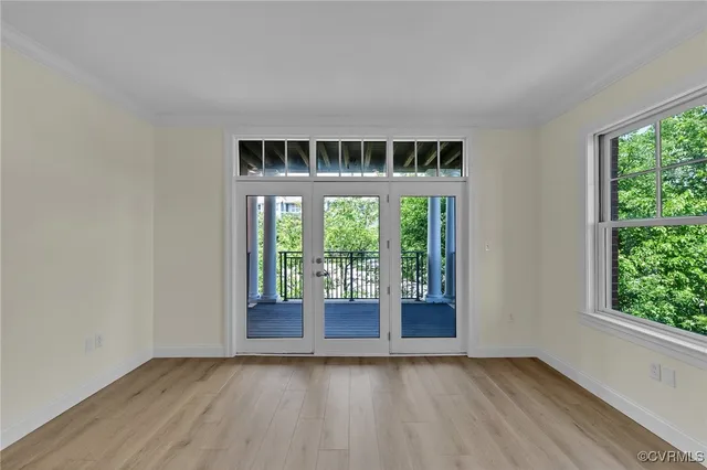 a view of an empty room with wooden floor and a window