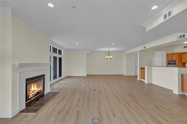 a view of an empty room with wooden floor fireplace and a window