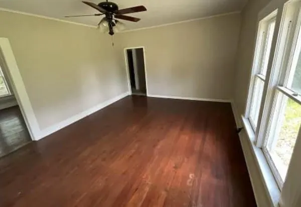 an empty room with wooden floor and windows