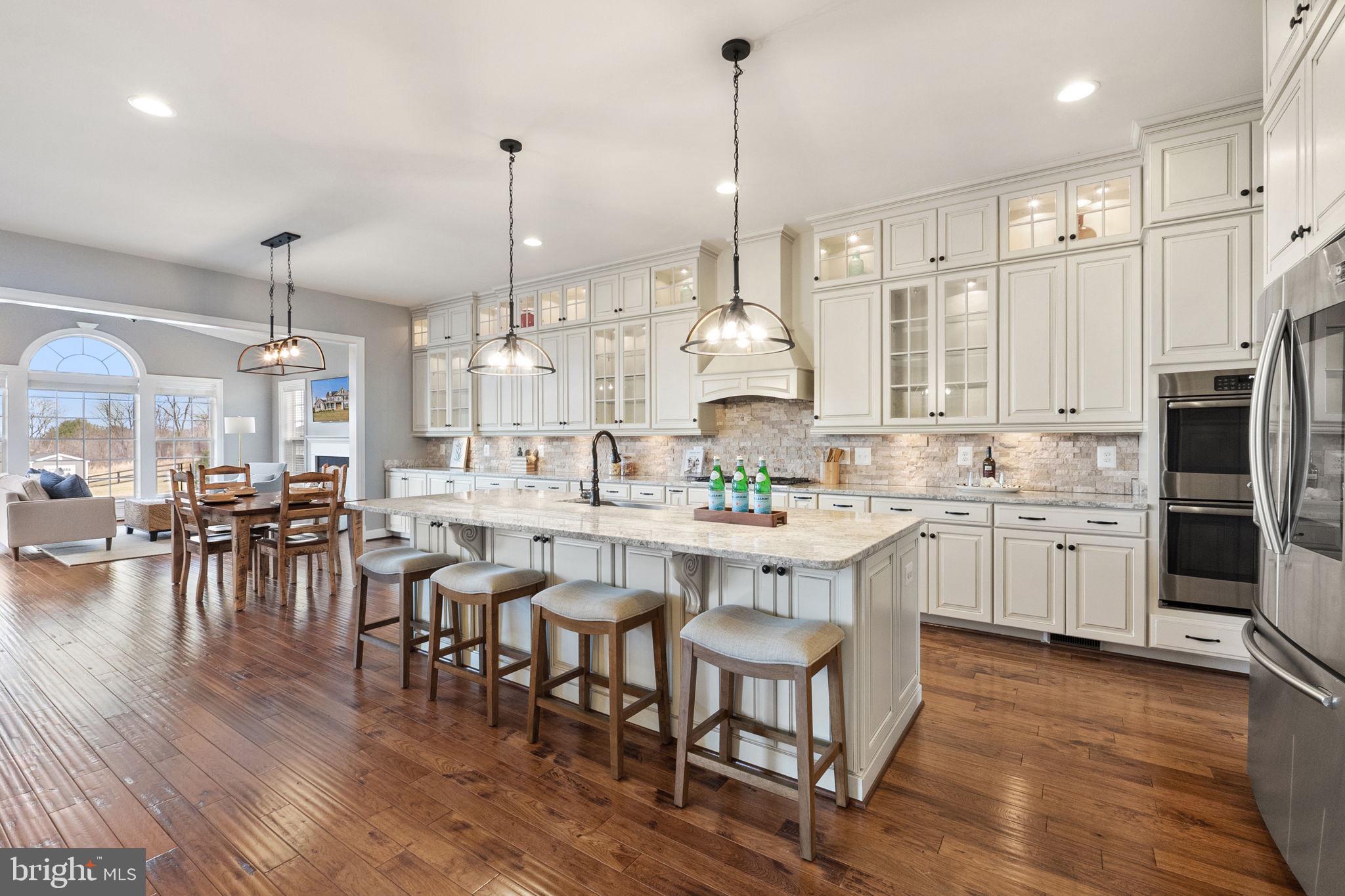18482 Wild Raspberry Drive Purcellville, VA 20132 - Photo 53 of 143 a kitchen with stainless steel appliances kitchen island granite countertop a table chairs stove and white cabinets