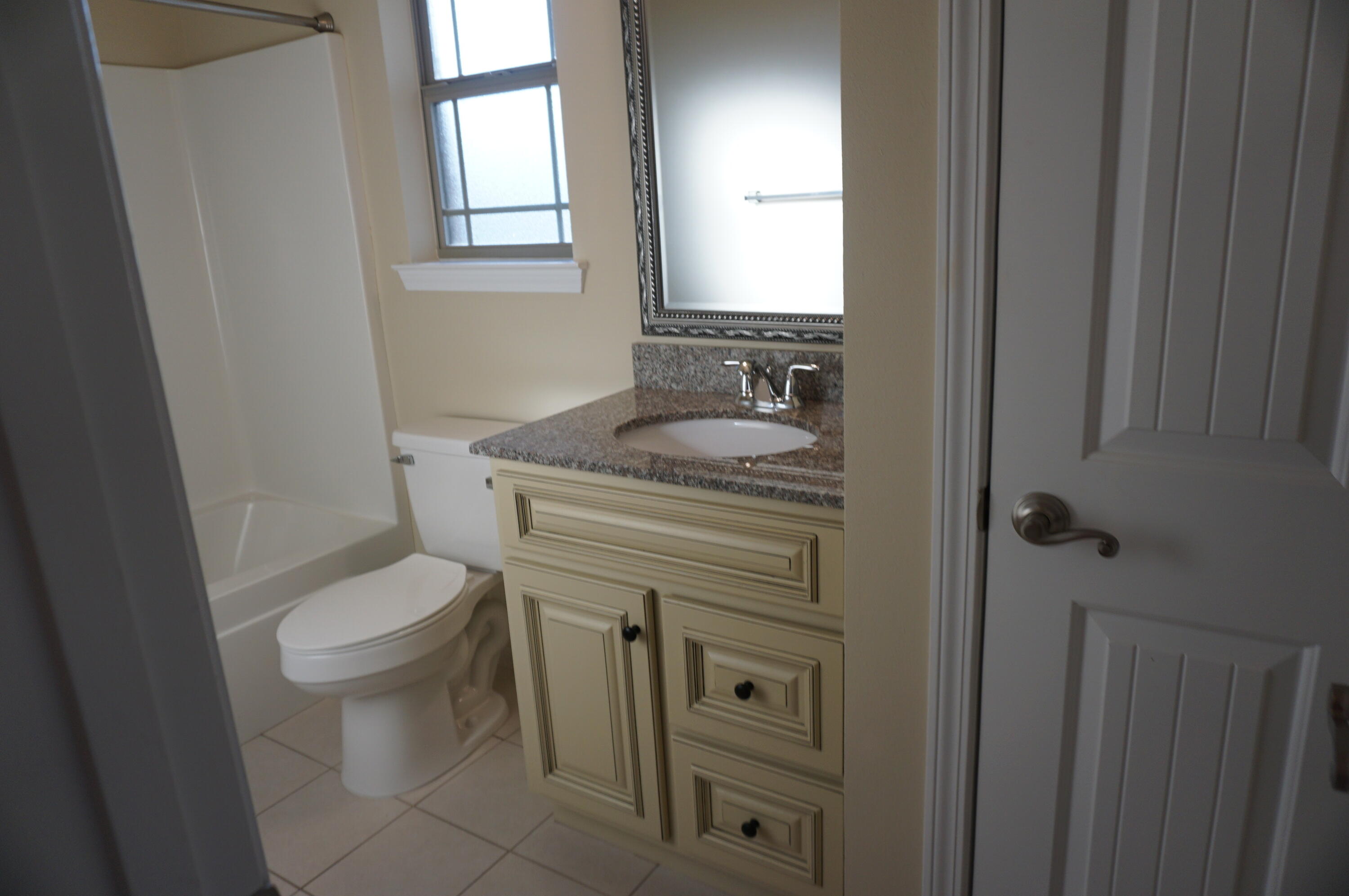 5263 Moore Loop Crestview, FL 32536 - Photo 18 of 37 a bathroom with a granite countertop toilet a sink a mirror and a window