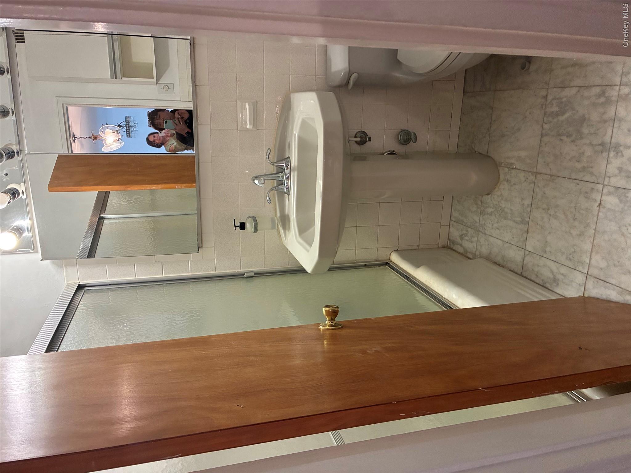 450 Shore Road, Unit 4H Long Beach, NY 11561 - Photo 10 of 17 a bathroom with a sink and mirror