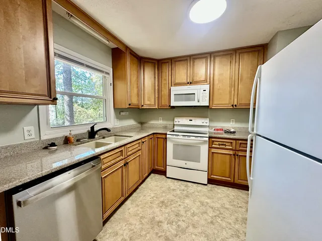 a kitchen with granite countertop cabinets stainless steel appliances a sink and a window