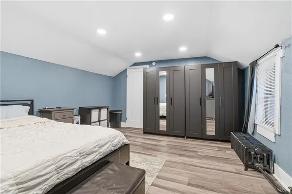 a large bedroom with a bed a dresser and a large mirror