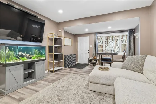 a living room with furniture a flat screen tv and floor to ceiling window