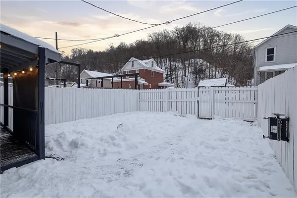 a view of a house with backyard and trees in the background