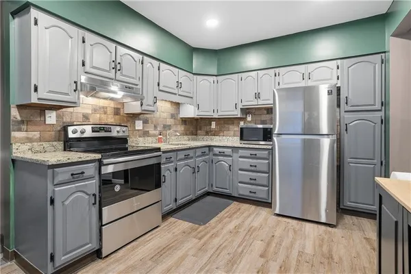 a kitchen with cabinets stainless steel appliances and a window