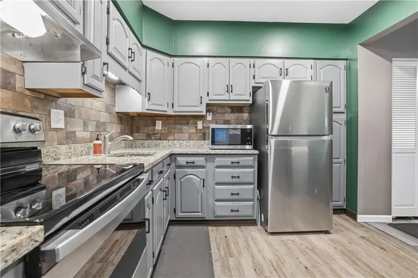a kitchen with granite countertop a refrigerator and a stove top oven