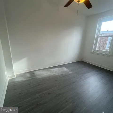 an empty room with wooden floor cabinet and windows