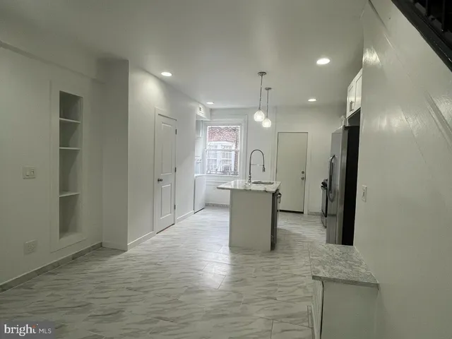a view of kitchen and empty room with wooden floor