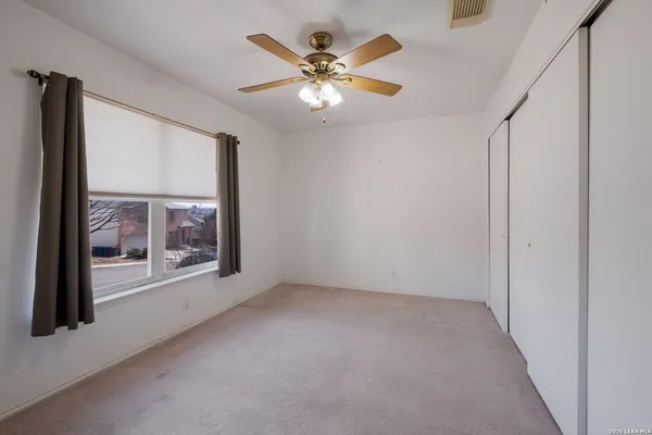 a view of an empty room with a window and a ceiling fan