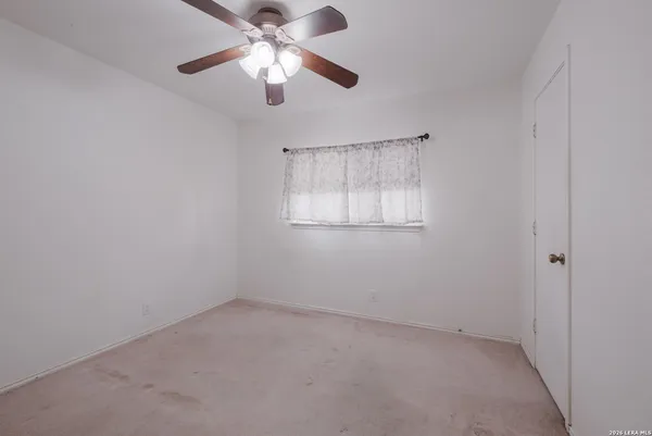 an empty room with a window and a fan