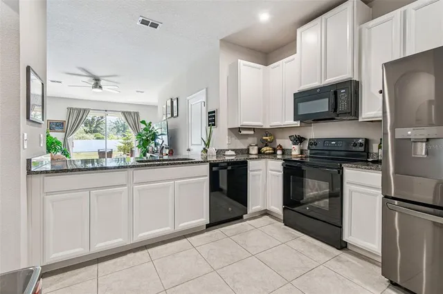 a kitchen with stainless steel appliances granite countertop a stove top oven a sink a dining table and chairs with wooden floor