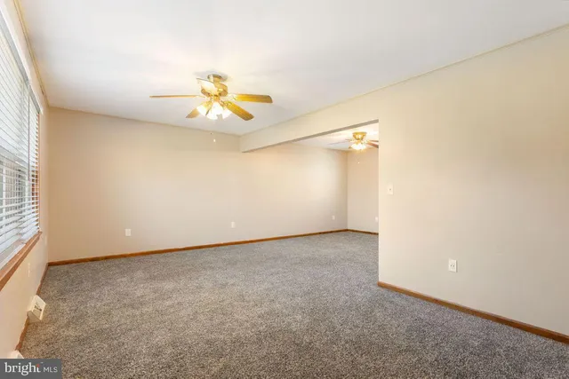 an empty room with a window and a ceiling fan
