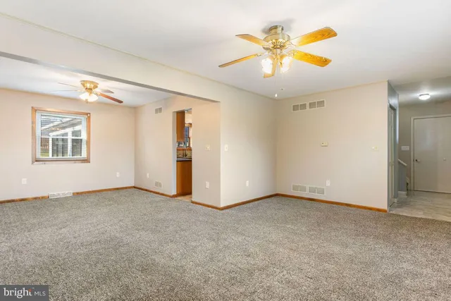 an empty room with a ceiling fan and window