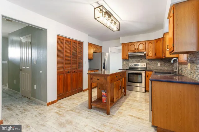 a kitchen with stainless steel appliances granite countertop a stove a sink dishwasher and a refrigerator with wooden floor
