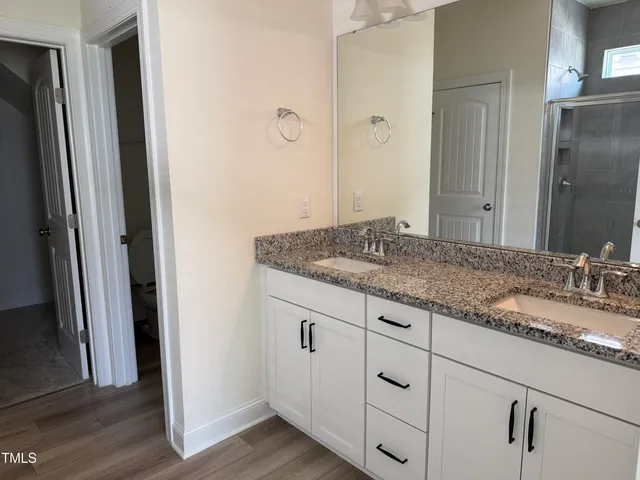 a kitchen with granite countertop a stove a sink and white cabinets with wooden floor