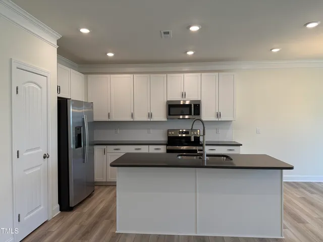 an empty room with wooden floor fireplace and windows