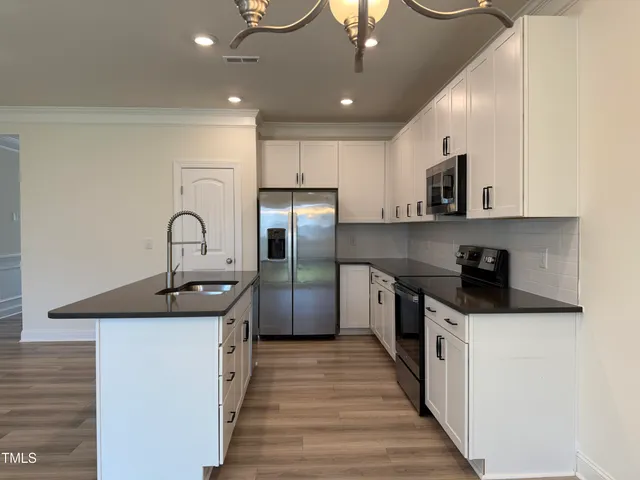 a kitchen with granite countertop a stove top oven and cabinets with wooden floor