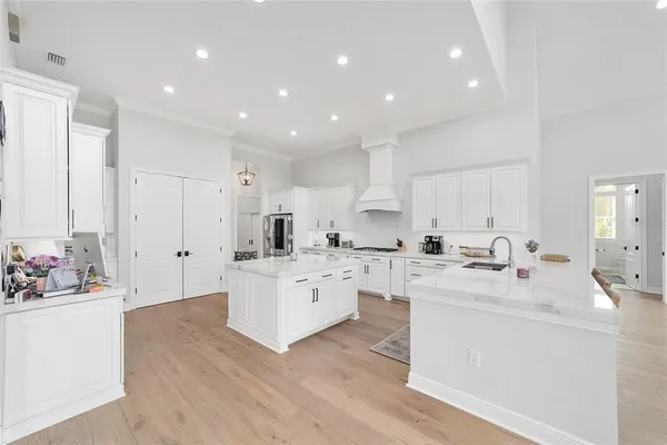 a large white kitchen with cabinets a sink and appliances