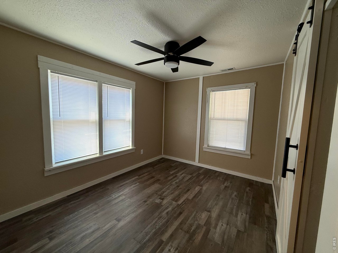 709 South 3rd Street Lamar, CO 81052 - Photo 12 of 20 an empty room with wooden floor a ceiling fan and windows