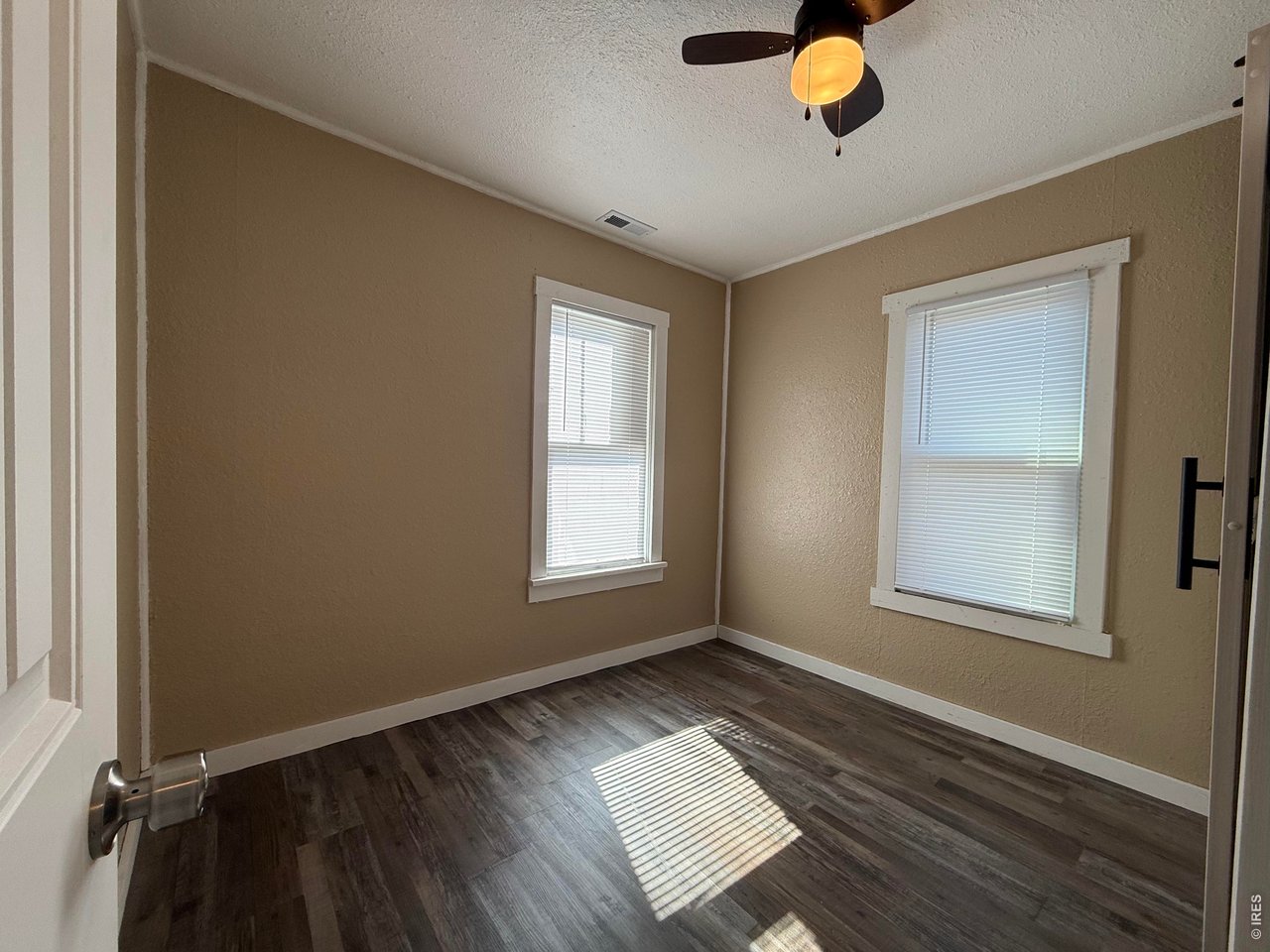 709 South 3rd Street Lamar, CO 81052 - Photo 14 of 20 an empty room with wooden floor and windows