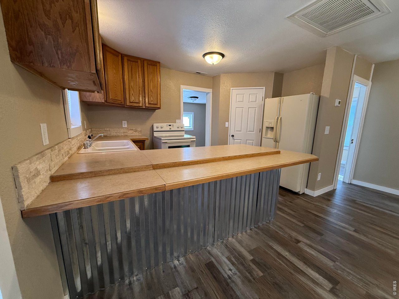 709 South 3rd Street Lamar, CO 81052 - Photo 7 of 20 a kitchen with stainless steel appliances wooden floor sink stove and cabinets