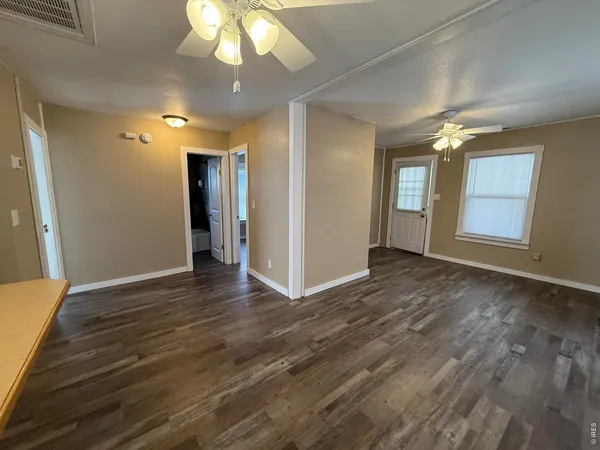 a view of an empty room with window and wooden floor