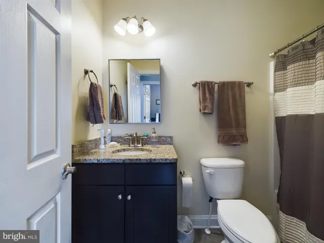a bathroom with a granite countertop toilet sink and mirror