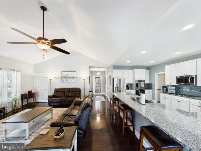 a living room with furniture kitchen view and a wooden floor